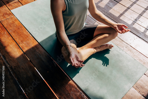 Low section of woman practicing yoga while sitting on exercise mat at wellness resort photo