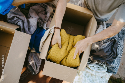 Directly above view of male volunteer packing sweater in box during charity drive at community center