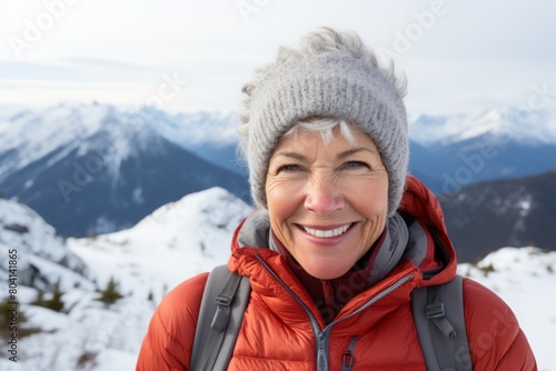 Portrait of a happy woman in her 50s wearing a thermal fleece pullover over snowy mountain range