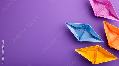 Colorful origami boats on purple background