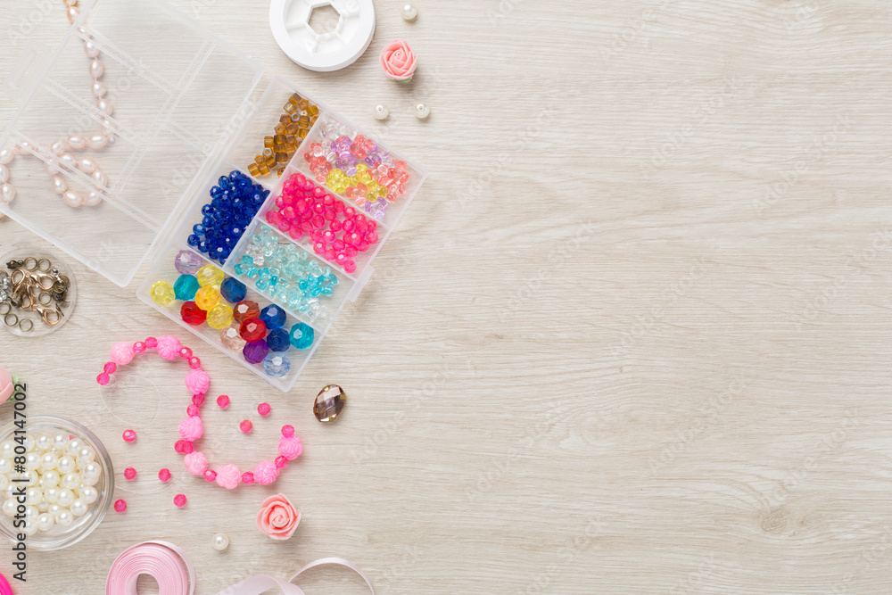 Tools and beads for making handmade jewelry on wooden background, top view