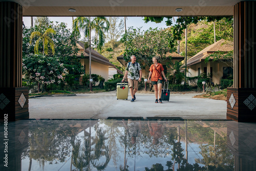 Full length of male and female tourists arriving with luggage at resort