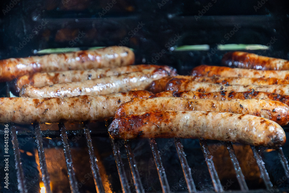 saucisses en cuisson sur une grille de barbecue, avec des flammes attisées par la graisse. saucisses en cuisson sur une grille de barbecue, avec des flammes attisées par la graisse.