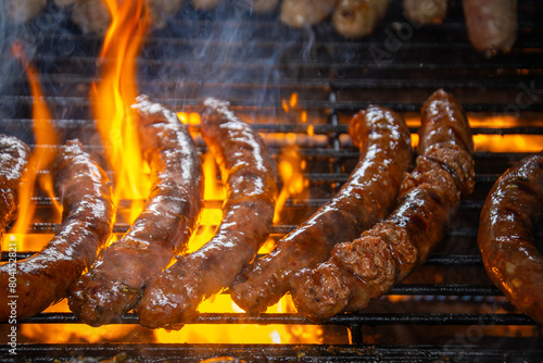 merguez en cuisson sur une grille de barbecue, avec des flammes attisées par la graisse. © ALF photo