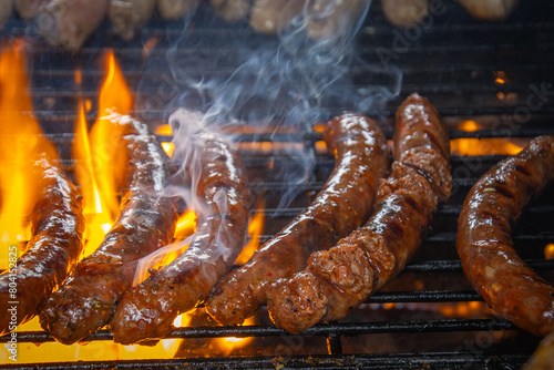 merguez en cuisson sur une grille de barbecue, avec des flammes attisées par la graisse. © ALF photo