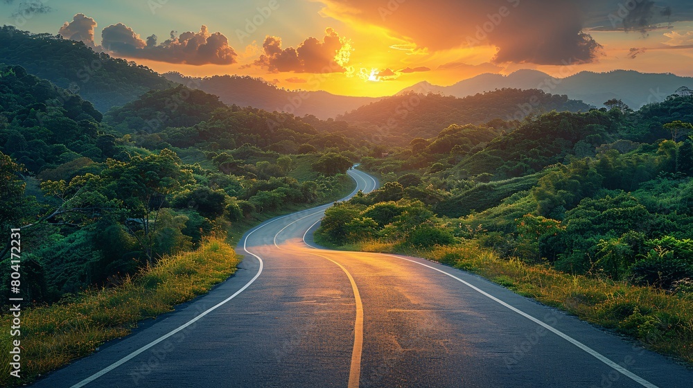 Sunrise over a mountainous landscape with a paved road.