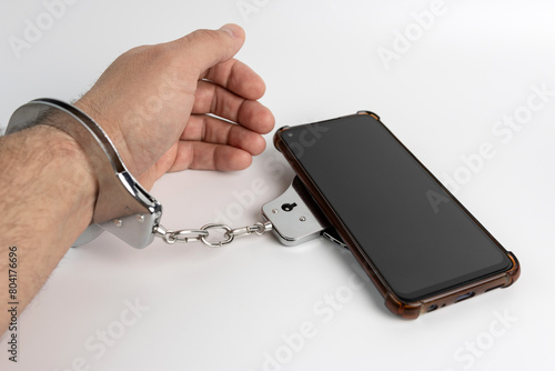 A man in handcuffs and a smartphone. Smartphone addiction concept.