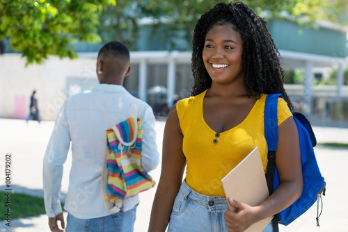 Beautiful black female student with backpack and male student in background