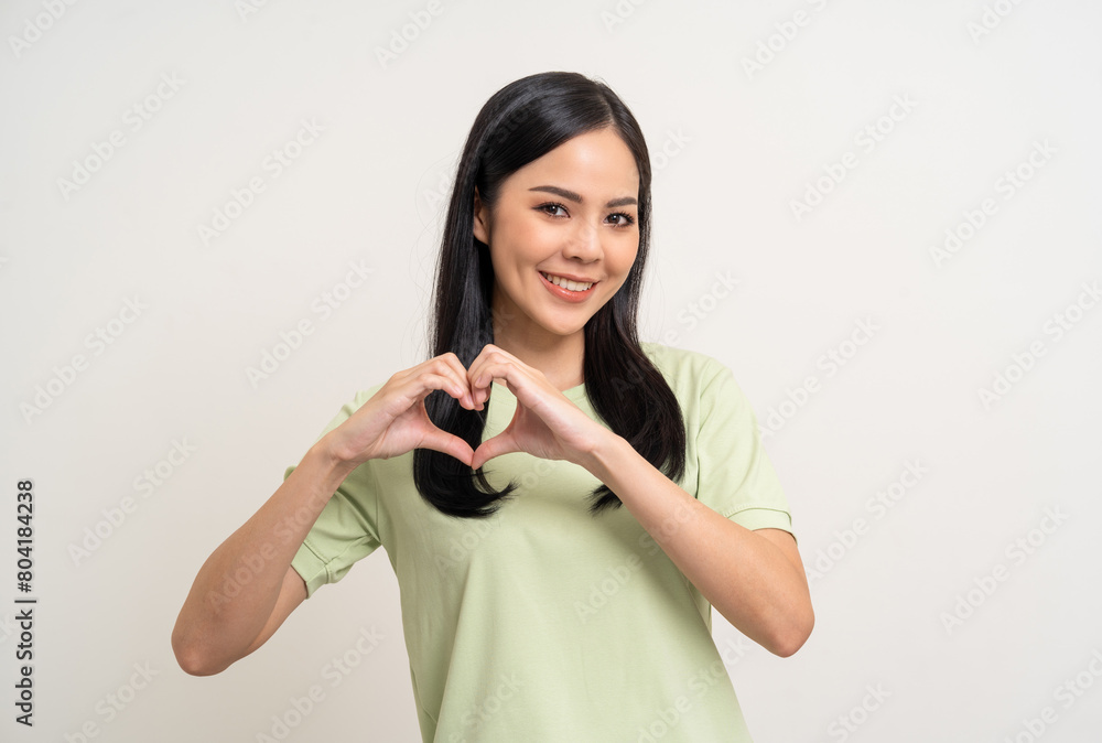 Pretty Young beautiful Asian woman standing and smiling showing heart sign on isolated white background. Lovely Latin female wearing green shirt feeling surprised and happy. Pretty Young beautiful Asian woman standing and smiling showing heart sign on isolated white background. Lovely Latin female wearing green shirt feeling surprised and happy.