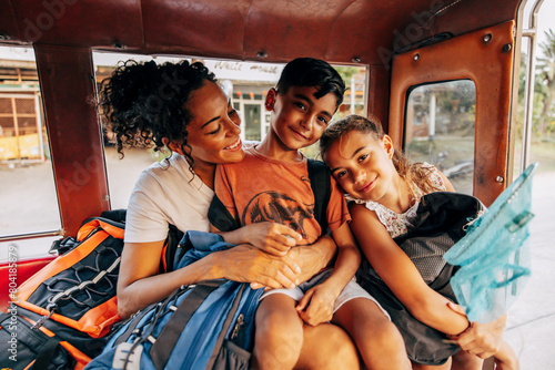 Portrait of smiling siblings traveling in tuk-tuk with mother on vacation photo