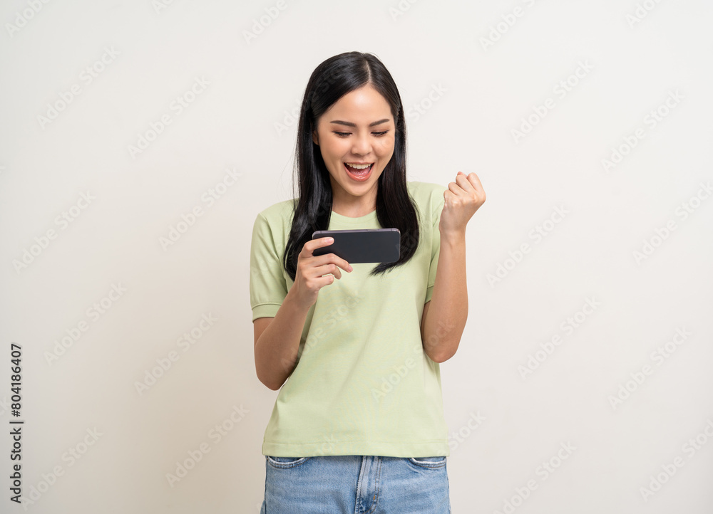 Excited Beautiful young asian women play mobile game and standing on isolated white background. Happy smiling female Playing game on smartphone winning victory moment. Very enjoy and fun relax time Excited Beautiful young asian women play mobile game and standing on isolated white background. Happy smiling female Playing game on smartphone winning victory moment. Very enjoy and fun relax time