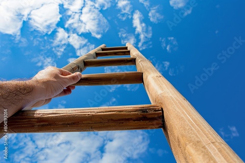 A closeup of a hand reaching for the first rung of a wooden ladder, set against a backdrop of a building facade photo