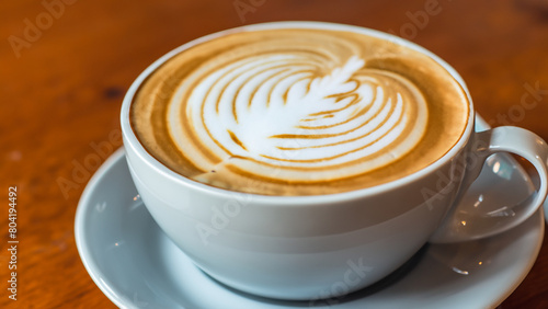 ceramic cup of coffee on table in coffee shop cafe.coffee cup latte art in cafe on wooden table.Classic Coffee Cup, Italian Cappuccino, Delicious Morning hot drink.