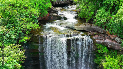 Dazzling tropical waterfall  cascading from towering cliff  captured by drone in lush forest paradise. Thung Na Muang Waterfall  Pha Taem National Park  Ubon Ratchathani Province  Thailand. 