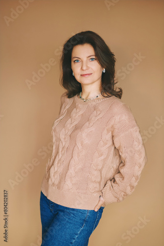 Studio portrait of beautiful 40 year old woman posing on beige background