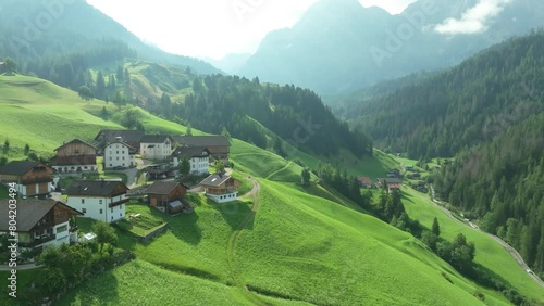 Cinematic aerial tilt up footage of the picturesque farm houses on the lush green hills of the La Val village in the Italian Dolomites. Cima Dieci and Cima Nove mountains. LuPa Creative. photo