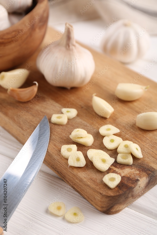 Aromatic cut garlic, cloves and bulbs on white wooden table, closeup Aromatic cut garlic, cloves and bulbs on white wooden table, closeup