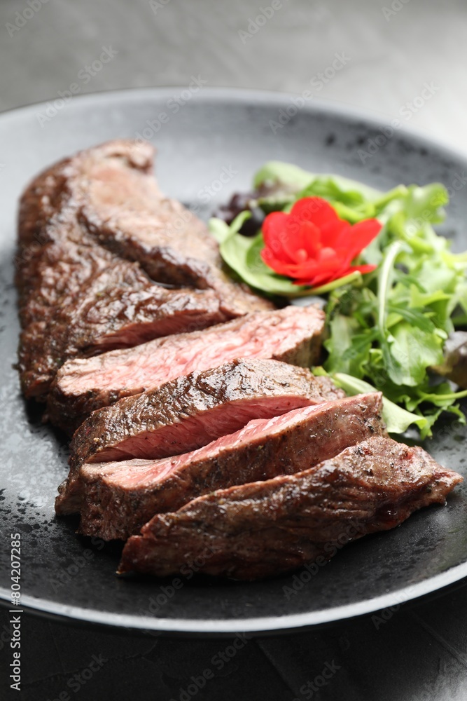 Pieces of delicious grilled beef meat and greens on table, closeup Pieces of delicious grilled beef meat and greens on table, closeup