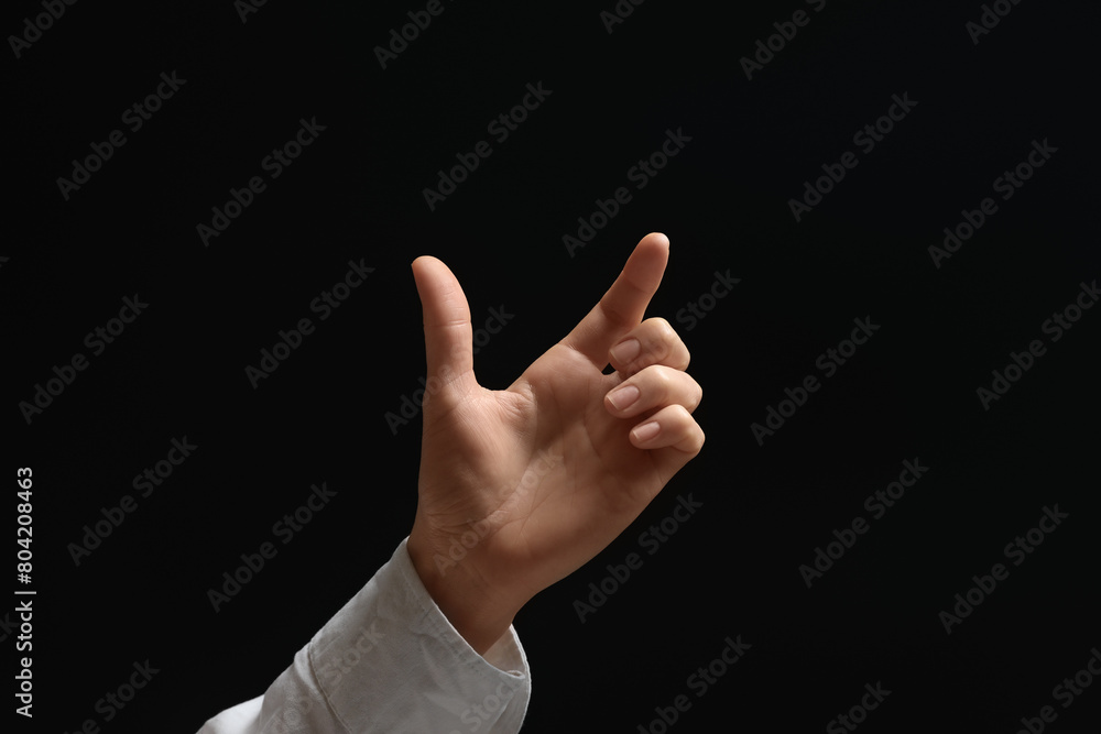 Woman holding something in hand on black background, closeup Woman holding something in hand on black background, closeup