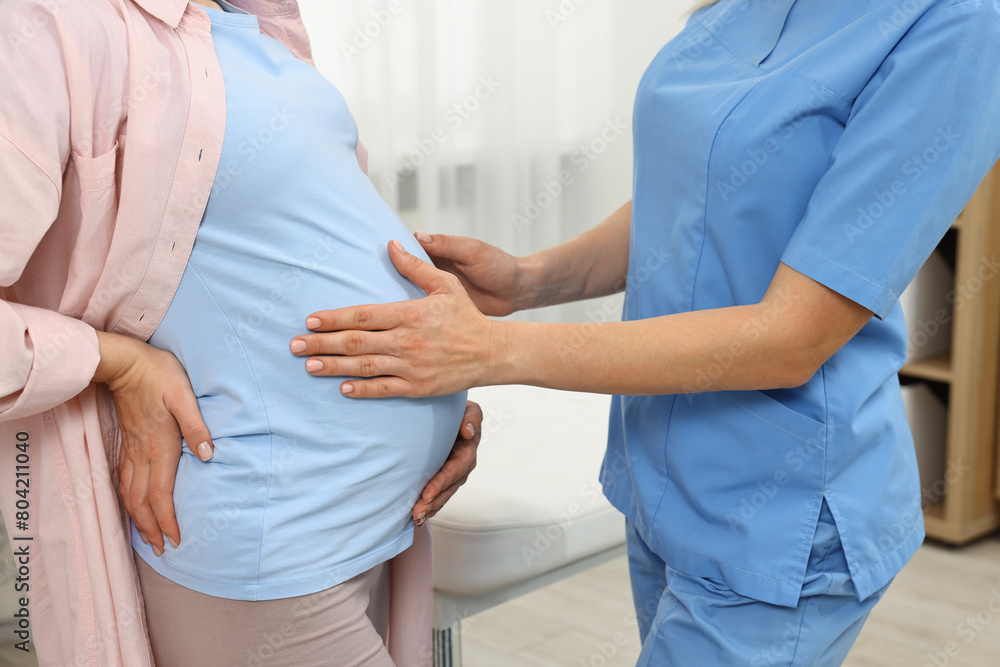 Pregnancy checkup. Doctor examining patient's tummy in clinic, closeup Pregnancy checkup. Doctor examining patient's tummy in clinic, closeup