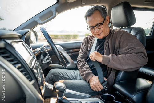 Senior asian men getting new car and putting on his seat belt before driving car. Safety drive concept.