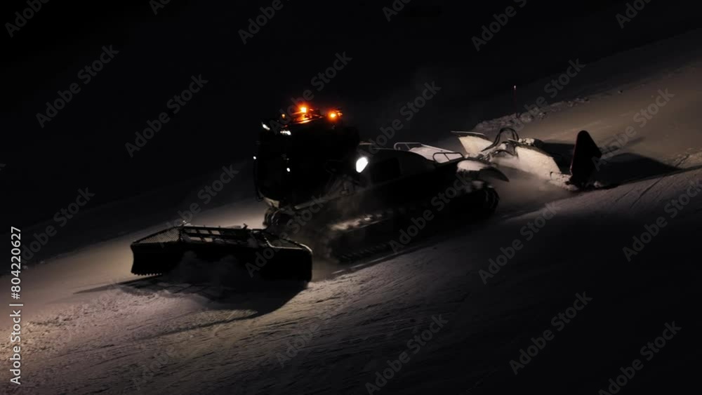 Snow groomer working at night in the Dolomites, Italy, bright lights against dark winter backdrop Snow groomer working at night in the Dolomites, Italy, bright lights against dark winter backdrop