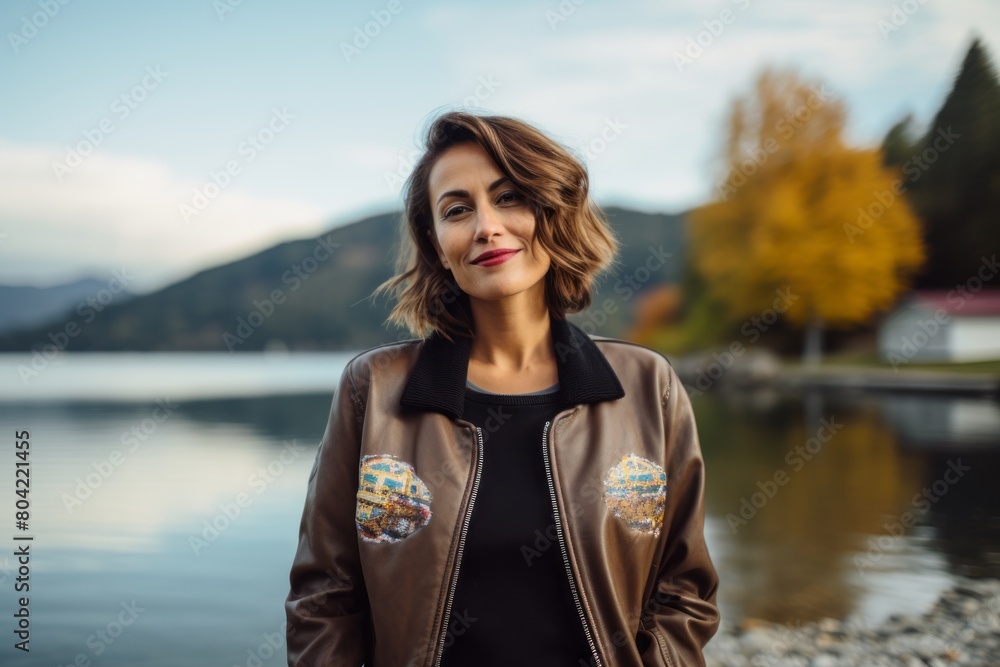 Portrait of a satisfied woman in her 40s wearing a trendy bomber jacket over serene lakeside view