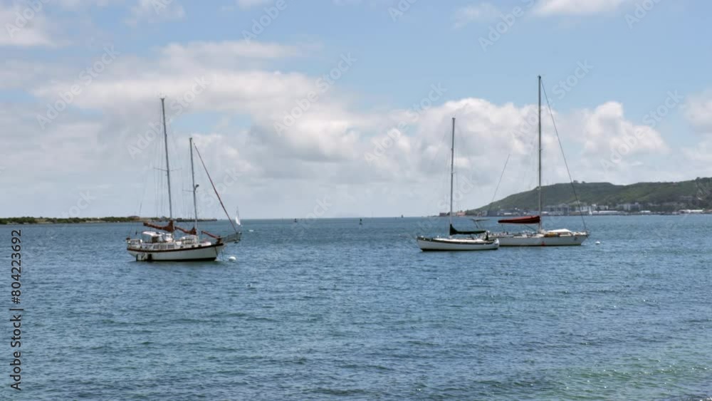 Sailboats docked and anchored in the sea. Waves crashing on sailboats at sea near coast Sailboats docked and anchored in the sea. Waves crashing on sailboats at sea near coast
