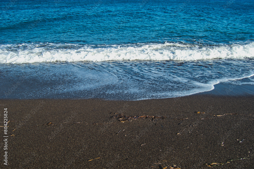 Plage de sable noir et village de Perissa, sur l'ile de Santorin, en Grèce, au mois d'avril 2024. Plage de sable noir et village de Perissa, sur l'ile de Santorin, en Grèce, au mois d'avril 2024.
