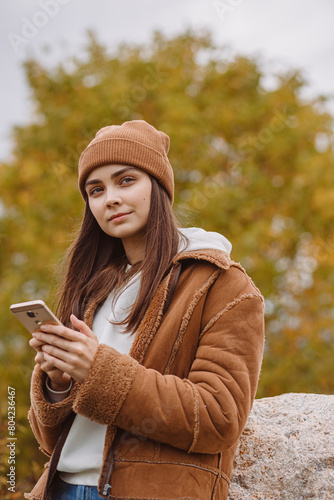 Young woman using smartphone in autumn park 