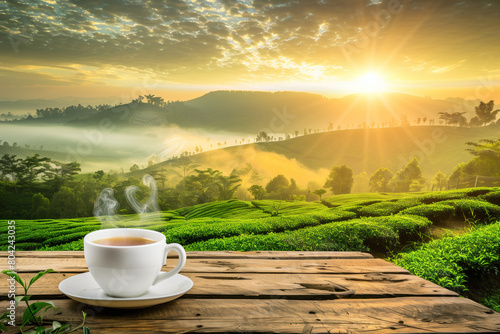 Steaming cup of tea on wooden table overlooking a serene tea garden at sunrise.