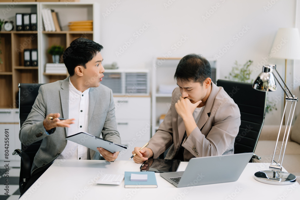 Furious two Asian businesspeople arguing strongly after making a mistake at work Furious two Asian businesspeople arguing strongly after making a mistake at work