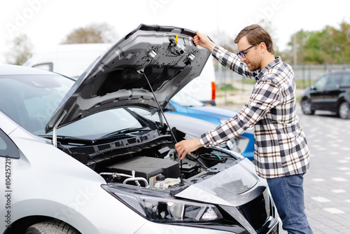 Bilde på lerret Young man checking under the hood of his car to figure out what the problem is