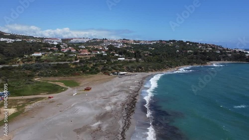 An aerial landscape showing the dynamic interface of a coastal town's architecture with the raw beauty of the sea, la playa del sardines, Spain, Cadiz, sotogrande  photo