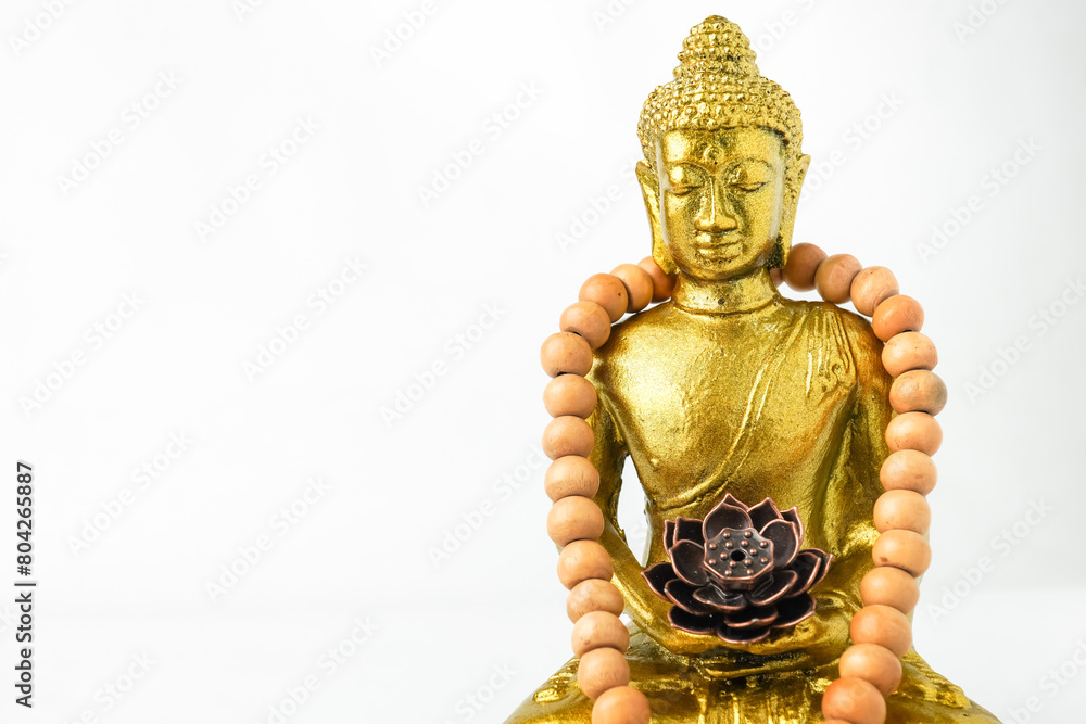 A golden statue of a Buddhist figure meditating and wearing prayer beads facing the front isolated on white background. Concept for Vesak Day and Enlightenment Day A golden statue of a Buddhist figure meditating and wearing prayer beads facing the front isolated on white background. Concept for Vesak Day and Enlightenment Day