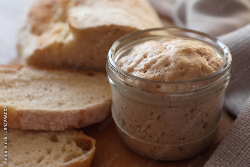 Sourdough starter in glass jar and bread on table, closeup Sourdough starter in glass jar and bread on table, closeup