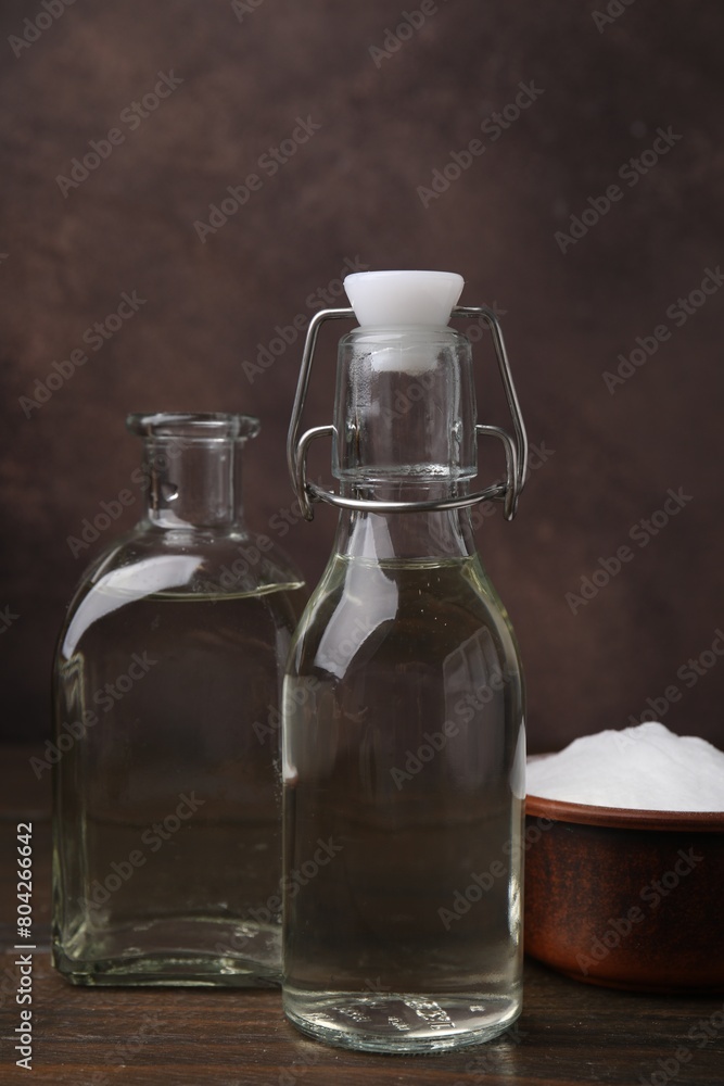 Vinegar in glass bottles and baking soda on wooden table Vinegar in glass bottles and baking soda on wooden table