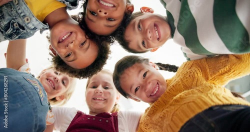 Huddle, support and happy children in school for education, community or development. Low angle, diversity and group of friends with smile in playground for solidarity, teamwork or playing together photo