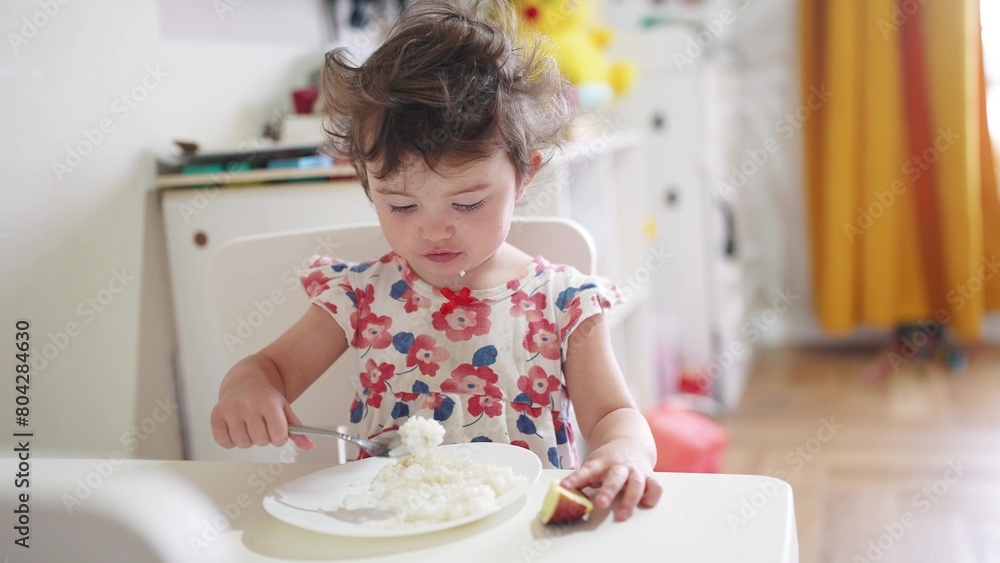the girl eats at the table. happy family child dream concept. girl sits indoors at a white table and eats food with her hands holding an apple in his hand. child's food lifestyle the girl eats at the table. happy family child dream concept. girl sits indoors at a white table and eats food with her hands holding an apple in his hand. child's food lifestyle