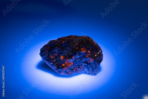 natural yooperlite gem stone in uv light on the white background photo