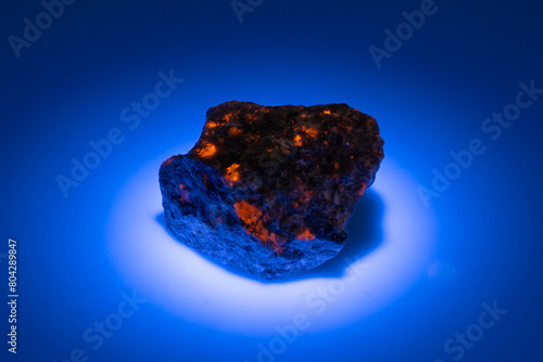 natural yooperlite gem stone in uv light on the white background