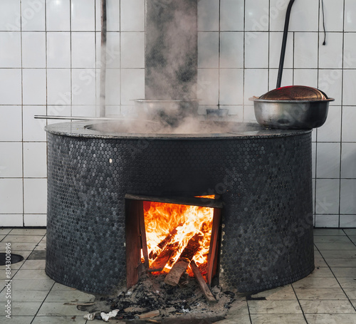 large cauldron on a wood stove with fire for cooking traditional Uzbek pilaf in a restaurant in Uzbekistan © alexkoral