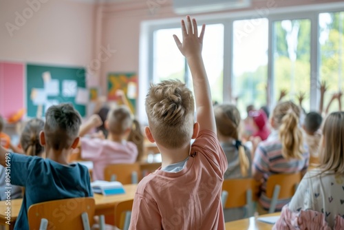 boy raising hand while answering in class at elementary school