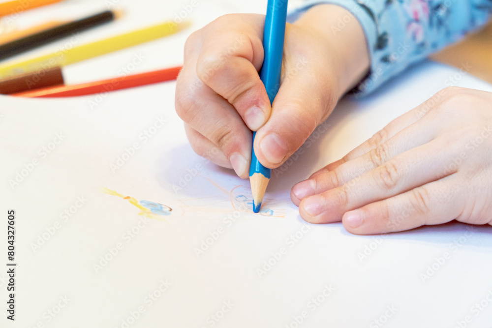 Close-up of a child's hands drawing with colored pencils. Children's creativity and development, fine motor skills, learning to write and draw. Close-up of a child's hands drawing with colored pencils. Children's creativity and development, fine motor skills, learning to write and draw.