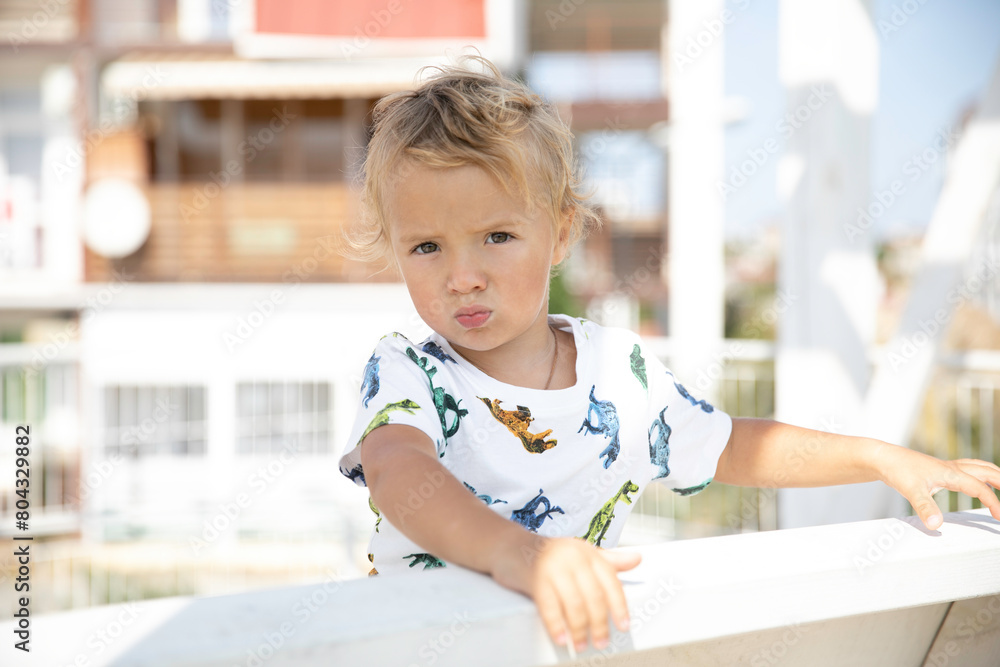 Little cute blond boy on a walk on a summer sunny day on a swing in the yard Little cute blond boy on a walk on a summer sunny day on a swing in the yard