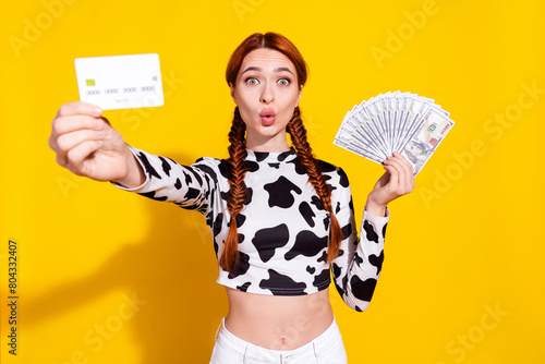 Photo of excited funky woman wear cow skin print top choosing credit card instead cash isolated yellow color background