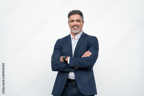Smiling confident latin hispanic mature business man standing crossed arms isolated on white background. Older senior businessman professional ceo, coach, leader looking at camera. Banner, copy space