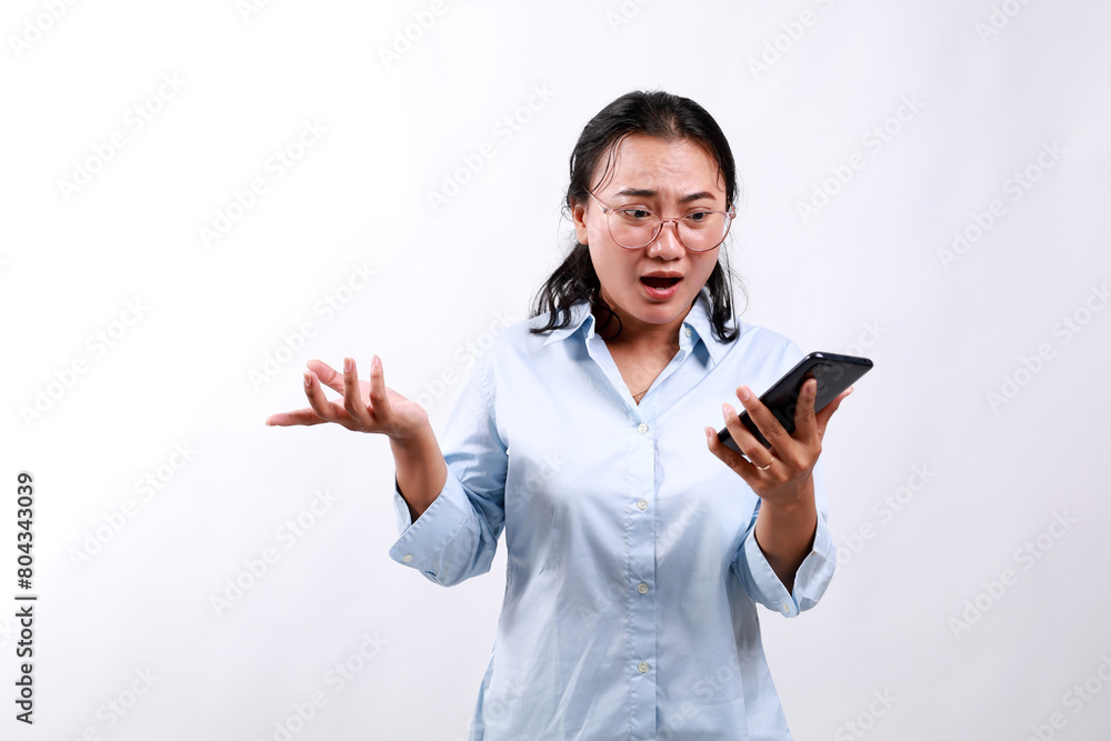 Angry asian business woman asking and shouting at mobile phone, looks outraged, furious while reading something on smartphone, standing over white background Angry asian business woman asking and shouting at mobile phone, looks outraged, furious while reading something on smartphone, standing over white background