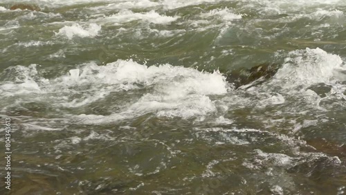 The movement of a mountain river, a stream flowing through the rocks. Close-up of river stones with running water, clear water flowing in a mountain river. water flowing in the river