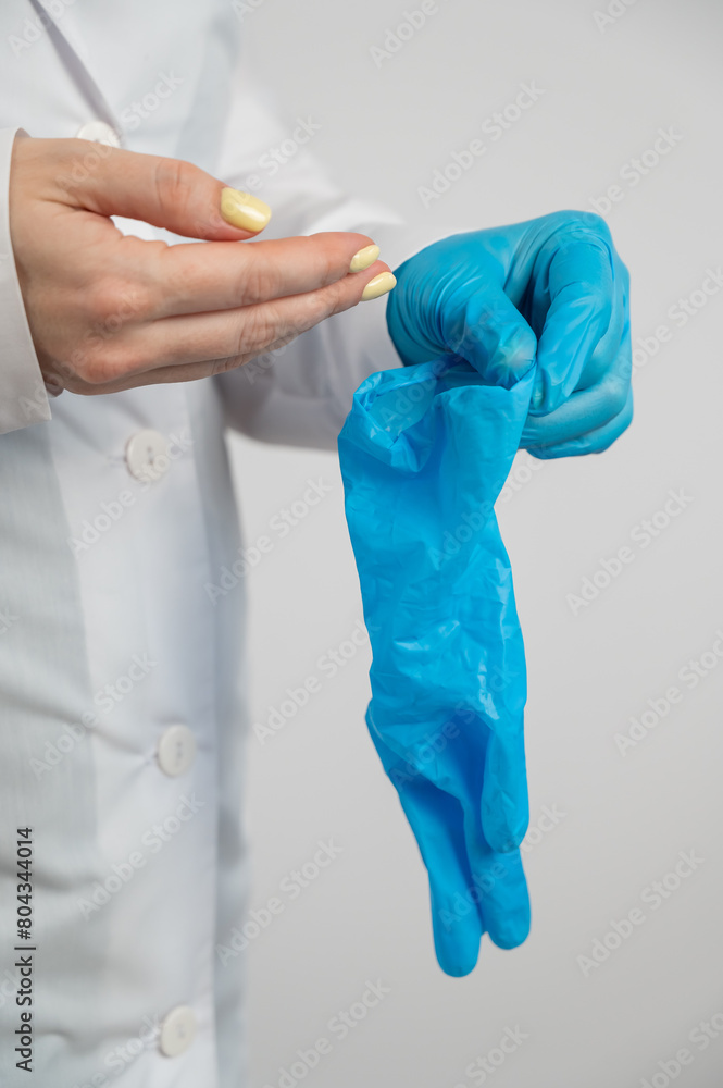 The doctor puts on latex gloves on a white background. Vertical photo. The doctor puts on latex gloves on a white background. Vertical photo.